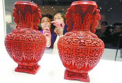 中国当代工艺美术双年展展览现场，几名观众正在认真地欣赏雕漆作品。本报记者 方非摄