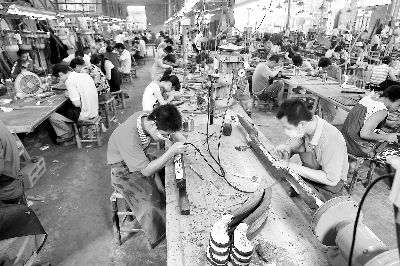 在仙作生产车间里，传统的斧凿敲击声、雕刻刀声和电锯、电钻、电磨声交汇，工人们正在精心制作红木古典工艺家具。