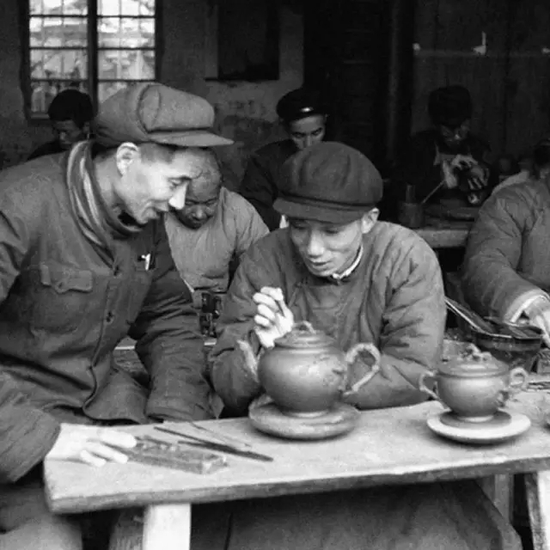 1955年顾景舟与朱可心正在讨论这件「松鼠葡萄十头套组茶具」的制作工艺照片