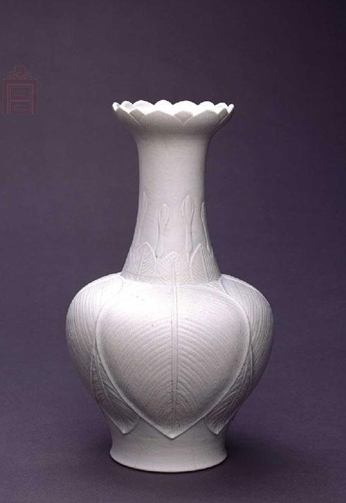 　　白釉凸雕莲瓣口瓶，清乾隆，高27.4cm，口径9.3cm，足径8.5cm。