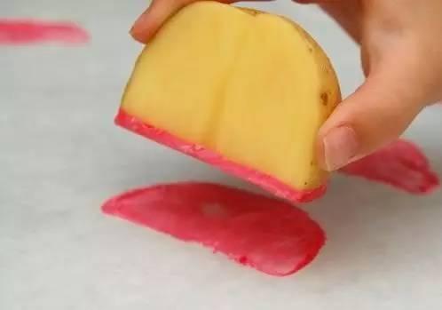 把一个土豆简单切成4瓣，在其中一瓣上涂上西瓜红颜料，直接印到包装纸上。