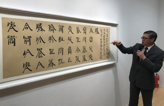 　展览现场，澳门艺术博物馆馆长陈继春介绍徐冰的萄文书法作品