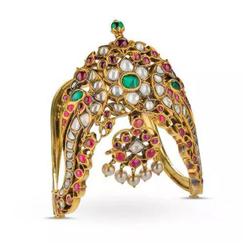 这种坚硬的臂环 （vanki） 通常由印度南部寺庙中的神像和舞者佩戴，而这件饰品华丽不凡，表明其曾供贵族使用。马杜赖 ? 19 世纪 ? 镶嵌在 22K 黄金中的钻石、红宝石、祖母绿和珍珠