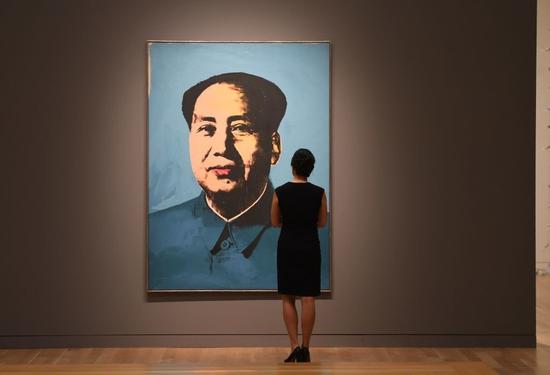 一位女士注视着安迪·沃霍尔的《毛泽东》。图片：TIMOTHY A。 CLARY/AFP/Getty Images