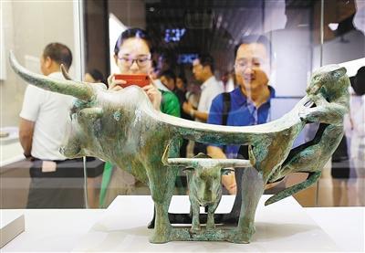 云南滇国青铜文化展展出的战国牛虎铜案吸引游客驻足观赏。 （首席记者 李明 实习生 徐楠 摄）