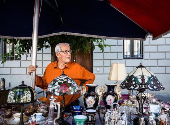 ↑8月4日，在意大利阿雷佐，一位商户在古董集市售卖商品。