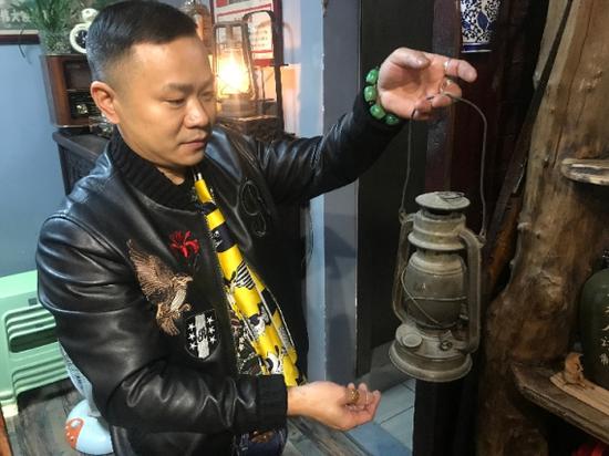 张晓明提起一盏老式煤油灯。新华社记者 谭晓红 摄